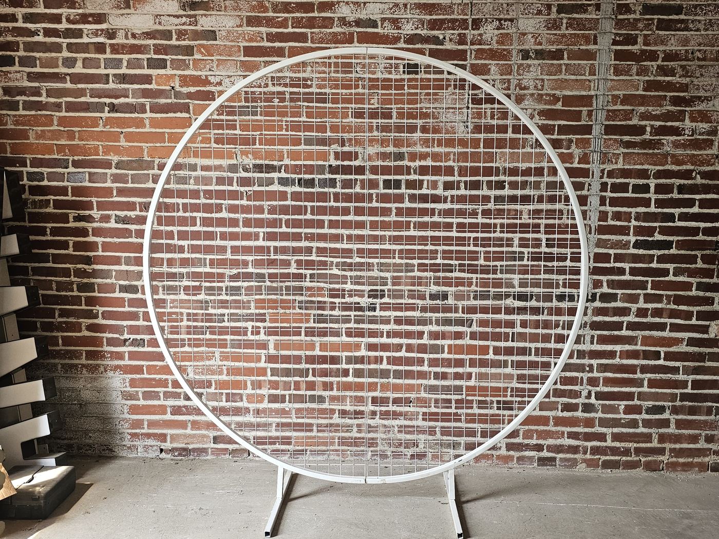 Round wedding backdrop frame, empty, against a brick wall