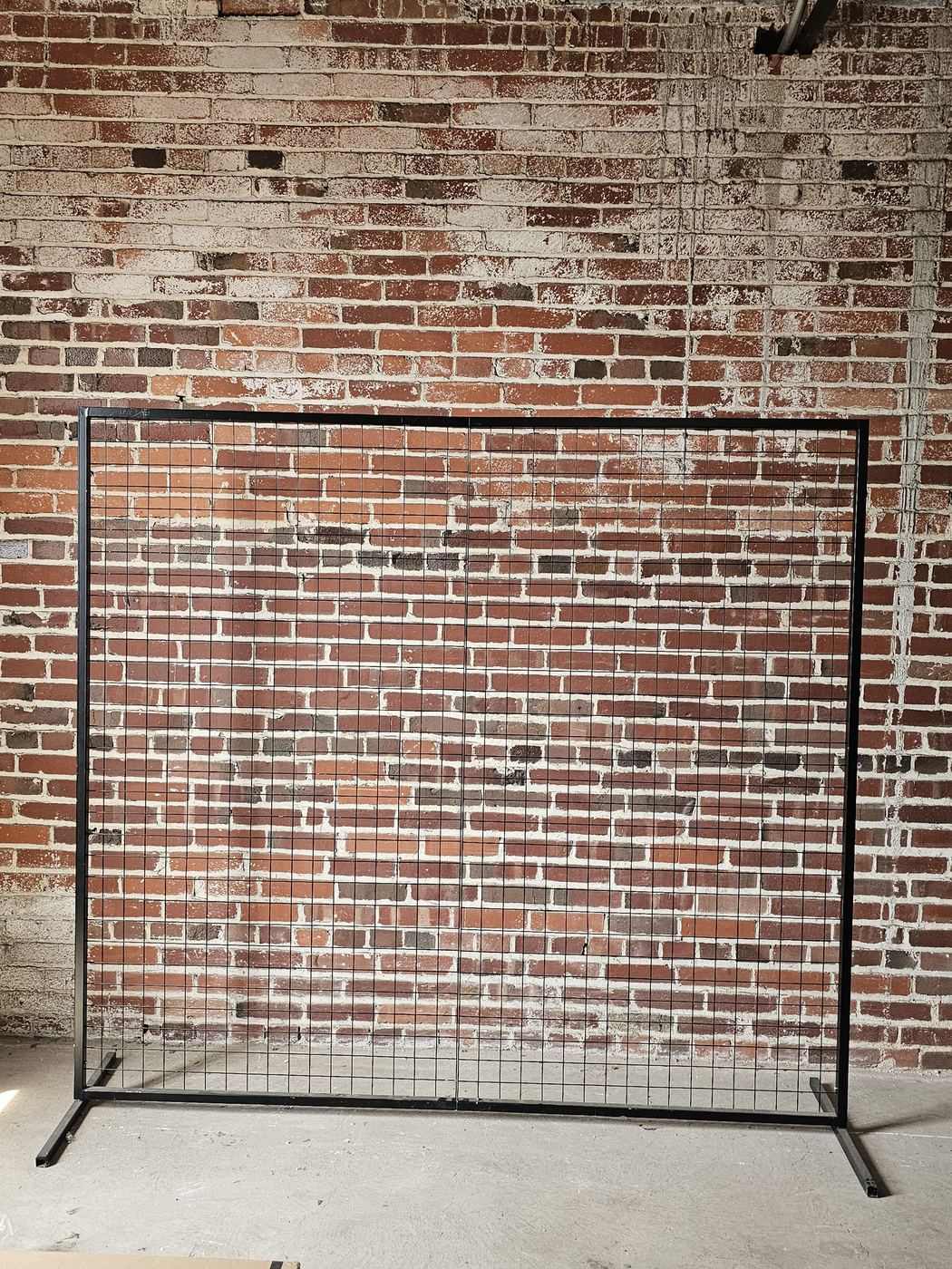 Black square wedding backdrop frame against a brick wall