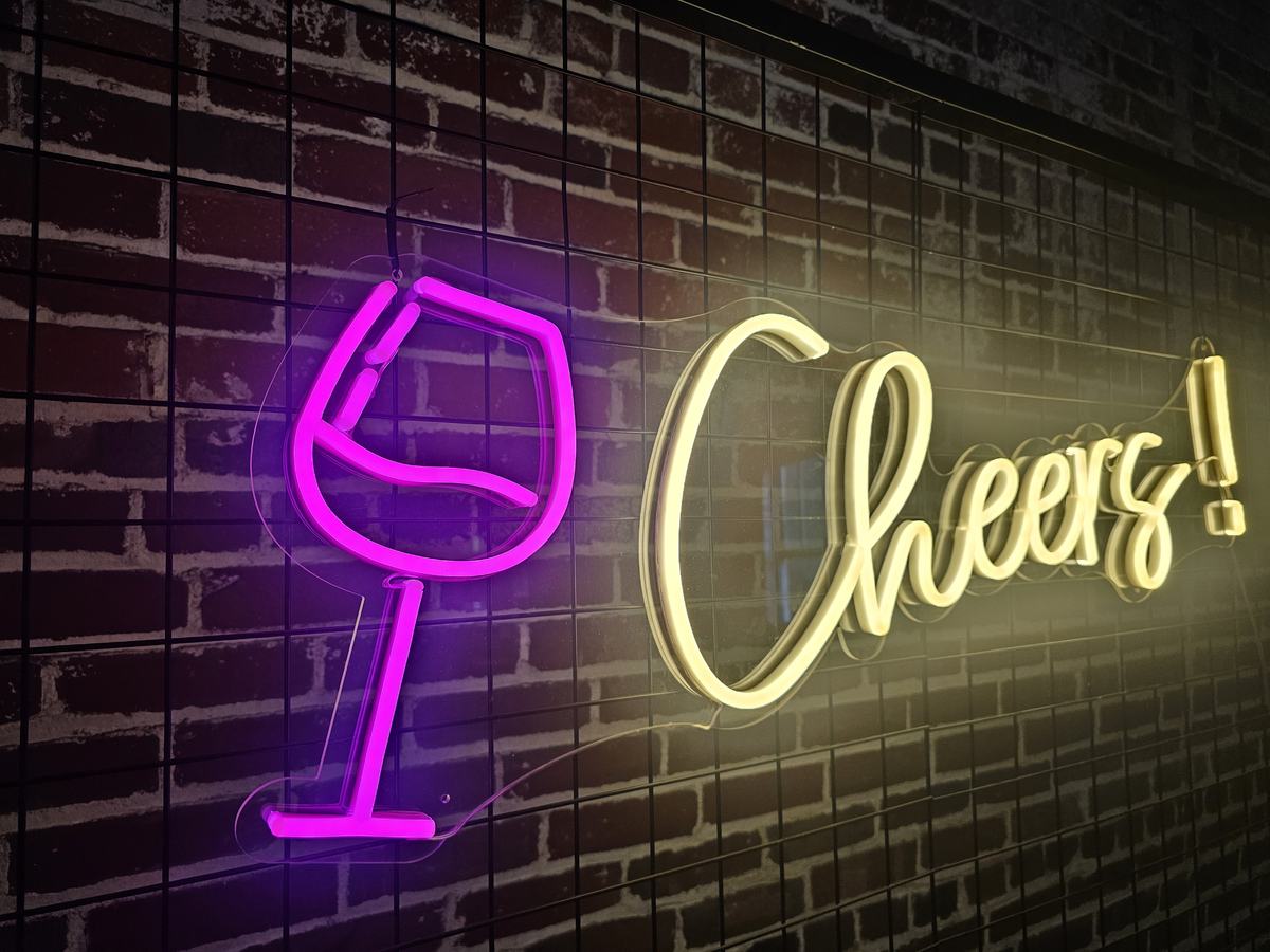 Cheers neon sign with wine glass icon on a brick wall