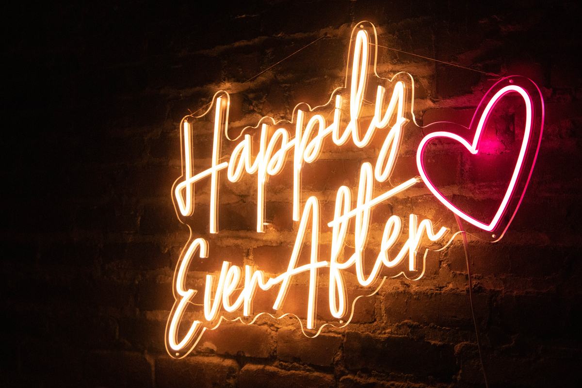 Happily Ever After script neon sign with heart accent on a brick wall